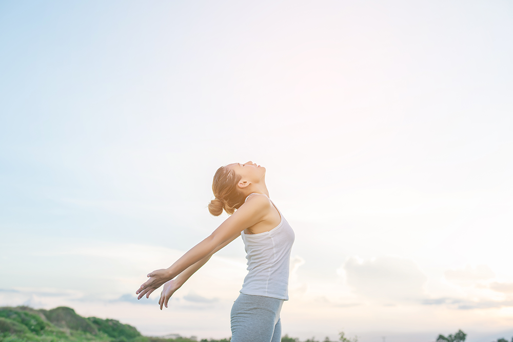 concentrated-woman-stretching-her-arms-with-sky-background